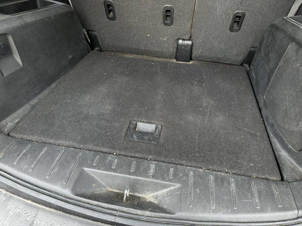SUV cargo area before detailing, with dust, ground-in dirt, and debris across the carpet and sill